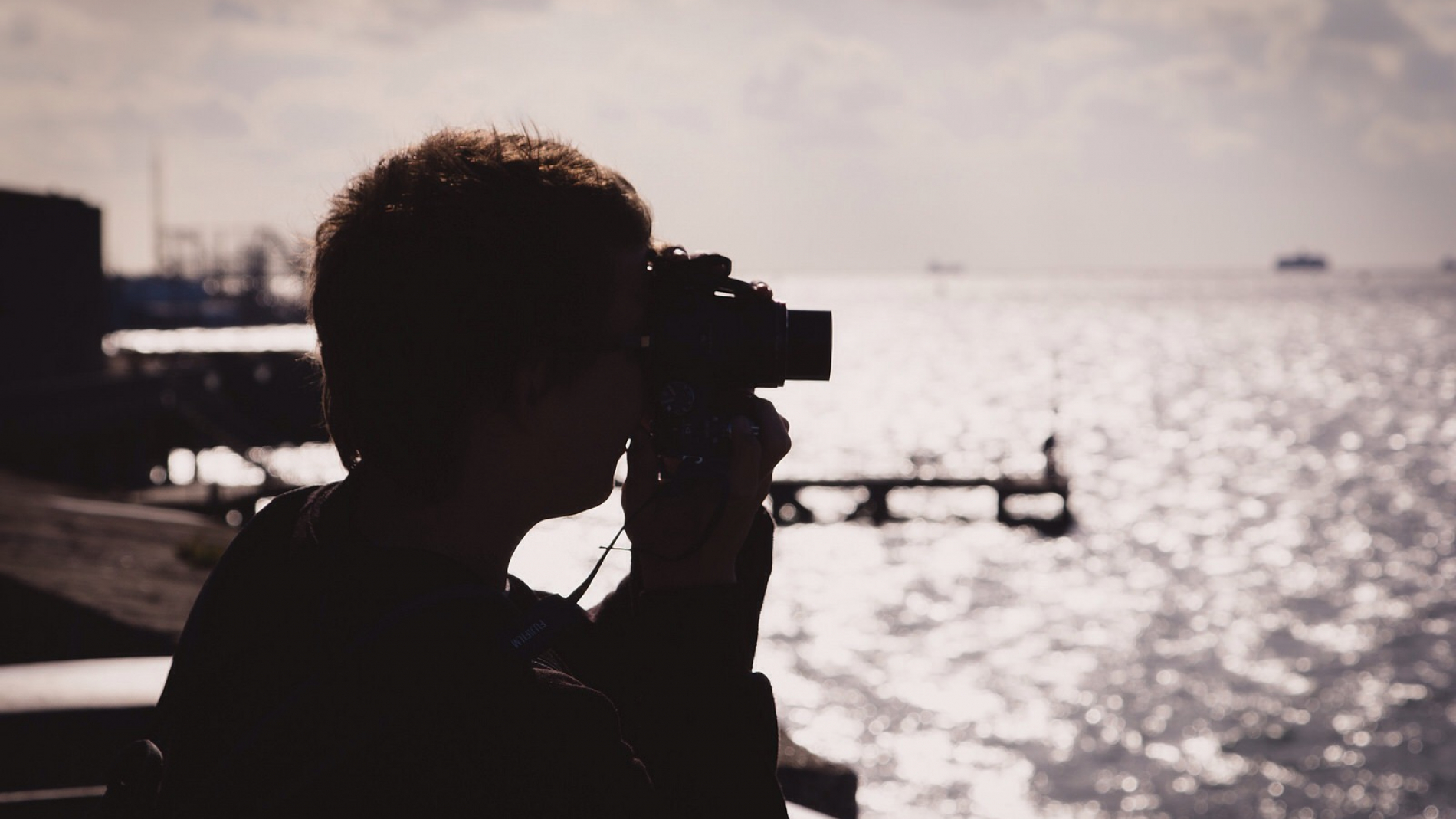 Silhouette of a photographer looking through their viewfinder at the golden light on The Solent