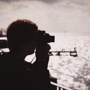 Silhouette of a photographer looking through their viewfinder at the golden light on The Solent