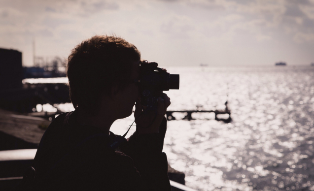 Silhouette of a photographer looking through their viewfinder at the golden light on The Solent