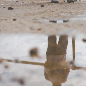 Reflection of a young photographer in a puddle of seawater at The Hotwalls