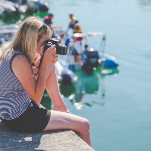 A young photographer sits on the quayside of The Camber taking a photo