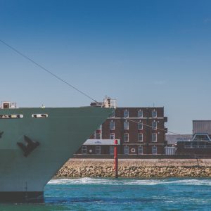 The bow of a large ship just in the frame as it enters Portsmouth Harbour