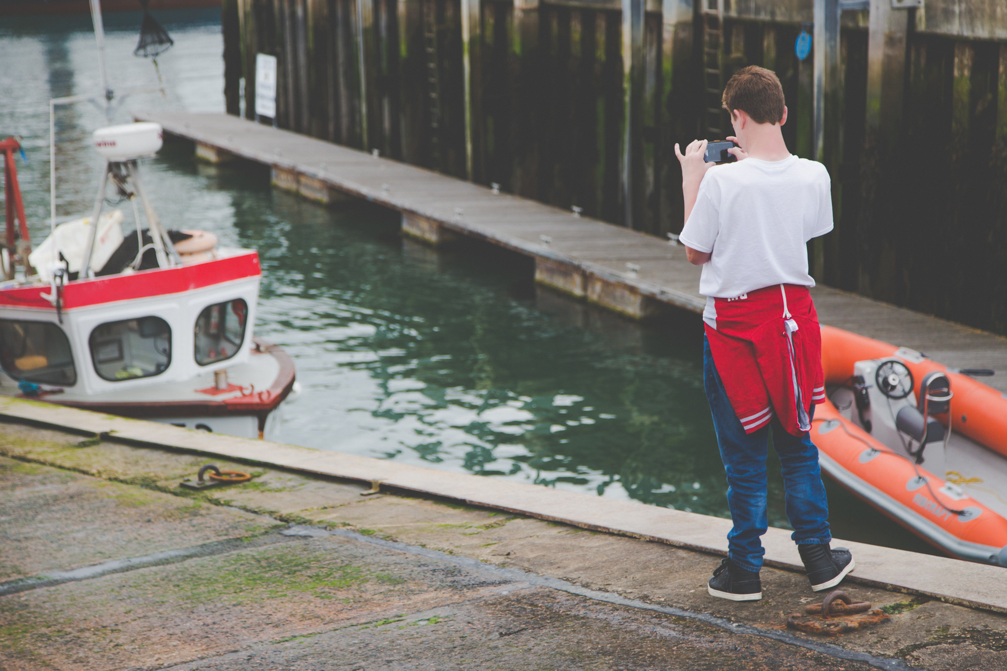 A photographer frames an image of a fishing boat at the enge of the water